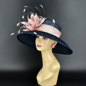 May include: A navy blue wide-brimmed hat with a pink feather embellishment and a pink ribbon.