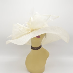 May include: A large, white, wide-brimmed hat with a large bow on the side. The hat is made of a delicate, woven material and has a soft, flowing shape.