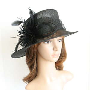 May include: A black wide-brimmed hat with a black feather and flower embellishment.