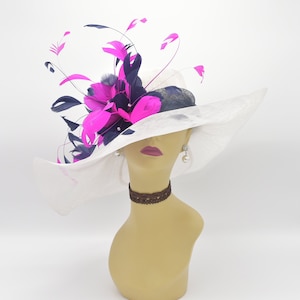 May include: A white wide-brimmed hat with a large pink and navy blue feather embellishment.