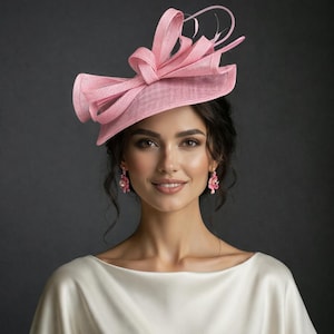 May include: A light pink, wide-brimmed hat with a large bow and decorative accents. The hat is made of a textured fabric and is worn with matching pink earrings. The background is a dark gray.