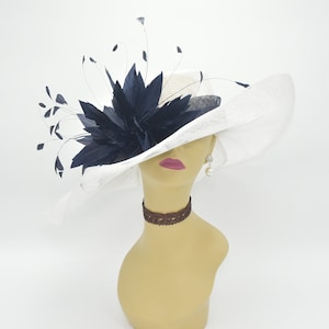 May include: A white wide-brimmed hat with a large black feather accent. The hat is made of straw and has a net-like texture.