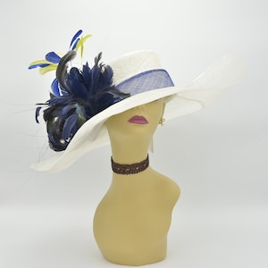May include: A white wide-brimmed hat with a blue ribbon and a blue and yellow feather accent.