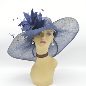 May include: A wide-brimmed navy blue hat with a large blue feather accent. The hat is made of a straw-like material and has a slightly curved brim.