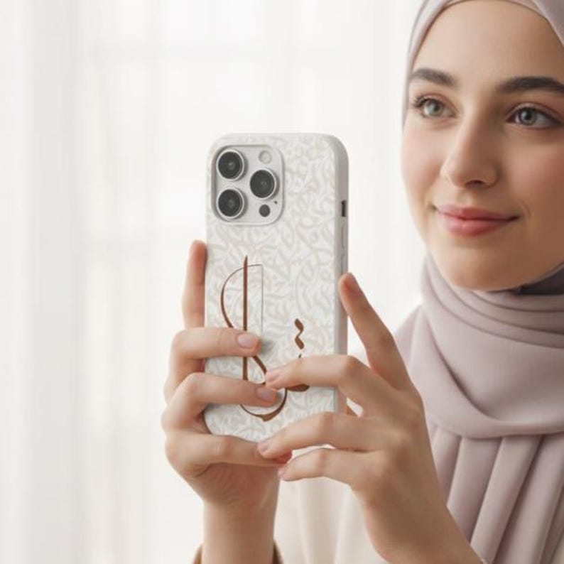 May include: A smartphone case featuring a light beige background with an intricate, repeating script pattern in a lighter shade. A prominent, stylized brown calligraphic symbol is centered on the back of the case, which has a triple-lens camera.