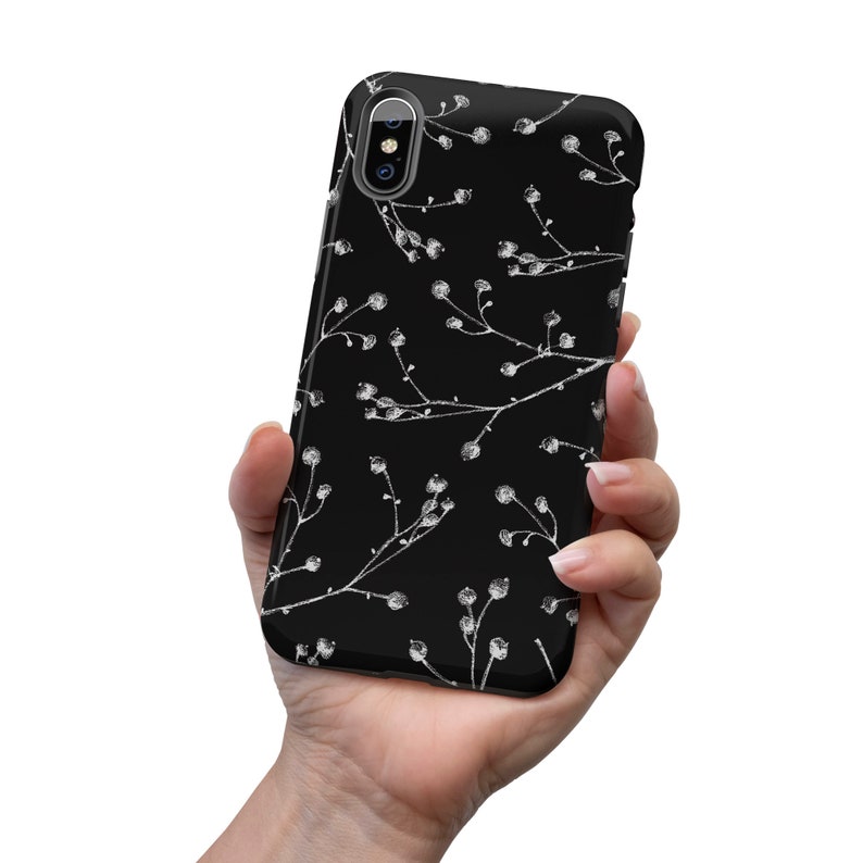 May include: Black phone case with a white floral pattern. The case has a cutout for the camera lens.