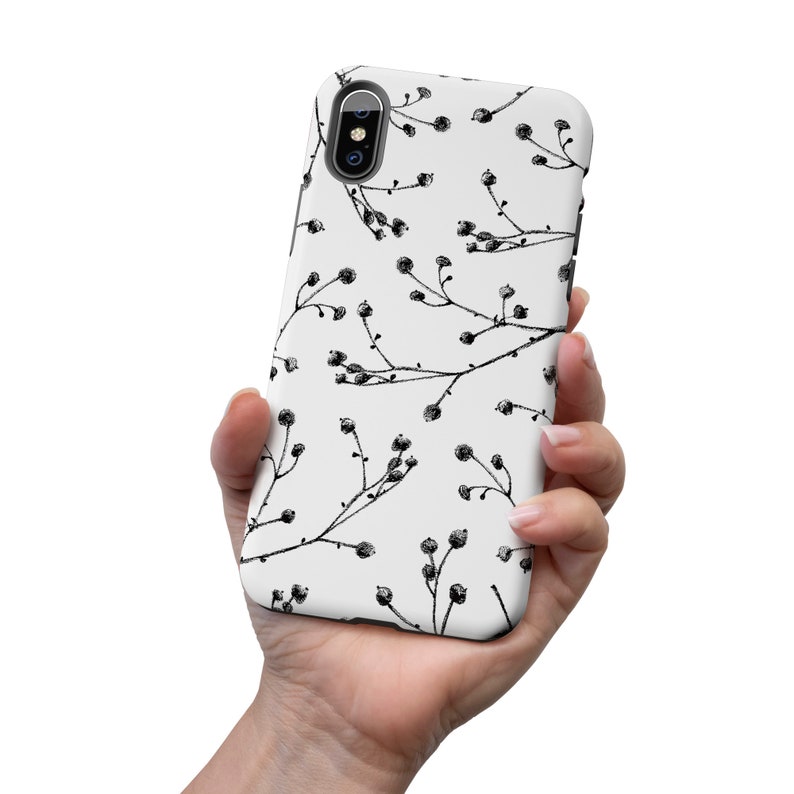 May include: A white phone case with a black and white floral pattern. The case has a camera cutout and a black border.