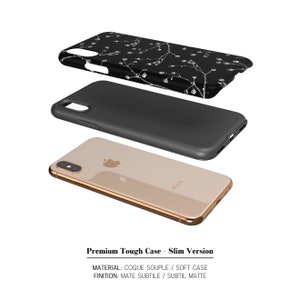 May include: A black phone case with a white floral pattern. The case is shown in three parts: the phone case itself, the black inner case, and the gold phone. The text "Premium Tough Case - Slim Version" is shown below the image. The text "MATERIAL: COQUE SOUPLE / SOFT CASE" and "FINITION: MATE SUBTILE / SUBTIL MATTE" is shown below the first text.