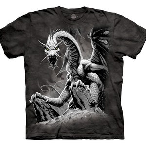 Pode incluir: Uma camiseta preta com um gráfico de dragão branco e cinza. O dragão é retratado com as asas abertas e as garras estendidas. Os olhos do dragão brilham em amarelo.