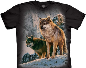 May include: A black t-shirt with a graphic print of two wolves in a snowy mountain landscape. The wolves are brown and gray with black noses and eyes. The background is a snowy forest with a mountain in the distance.