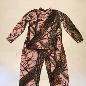 Puede incluir: Pijama de camuflaje rosa y marrón con mangas largas y pantalones.