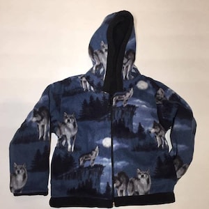 May include: A blue fleece jacket with a black hood and zipper closure. The jacket features a wolf print pattern on a dark blue background.