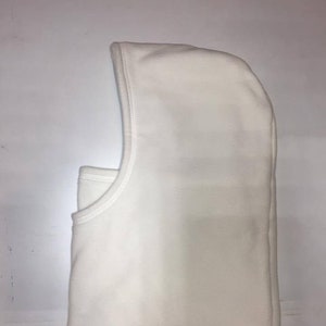 Może przedstawiać: Biała kominiarka, osłona głowy i twarzy, jest prezentowana na białym tle. Kominiarka ma kaptur i otwór na twarz. Krawędzie są starannie zszyte. To zimowe akcesorium ma zapewnić ciepło i ochronę.