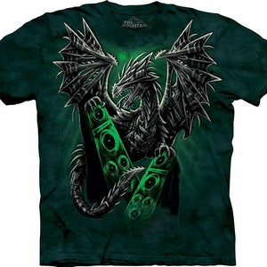 Pode incluir: Uma camiseta verde com um dragão preto e verde segurando duas caixas de som grandes. O dragão tem uma aparência mecânica e as caixas de som brilham em verde. A camiseta tem o texto "The Mountain" na parte superior.