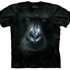 May include: Black t-shirt with a close-up image of a gorilla's face. The gorilla's eyes are brown and the image is printed on the front of the shirt. The shirt has a tag that says "The Mountain".