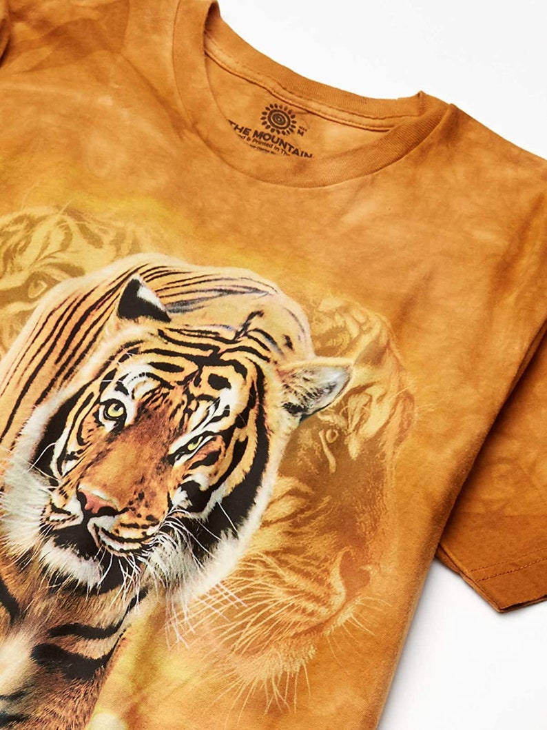 May include: A brown tie-dye t-shirt with a large image of a tiger's face. The shirt has the text "The Mountain" printed on the tag.