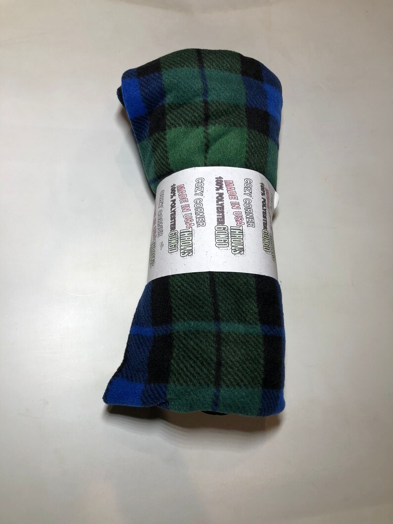 Puede incluir: Una manta de forro polar a cuadros verde, azul y negro enrollada con el texto "COZY CORNER THROWS MADE IN USA 100% POLYESTER 60X60" impreso en la etiqueta.