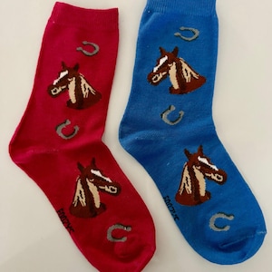 May include: A pair of crew socks, one red and one blue, each featuring a horse head and horseshoe design. The horse heads are brown and white, and the horseshoes are gray. The socks have the word "FOOZY" printed on them.