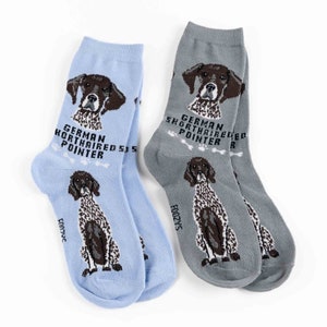 May include: A pair of socks featuring a German Shorthaired Pointer dog. One sock is light blue with the text "German Shorthaired Pointer" and the other sock is gray with the text "German Shorthaired Pointer".