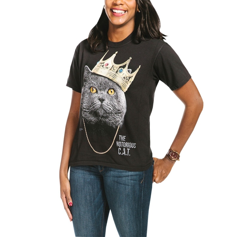 May include: A black t-shirt with a gray cat wearing a gold crown and a gold chain. The text "THE NOTORIOUS C.A.T." is printed on the shirt.