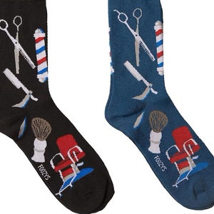 May include: A pair of novelty socks, one black and one blue, each patterned with barber shop tools. The designs include scissors, a straight razor, a shaving brush, a barber pole, and a barber chair. The brand name "FOOZY'S" is printed on the bottom of each sock.