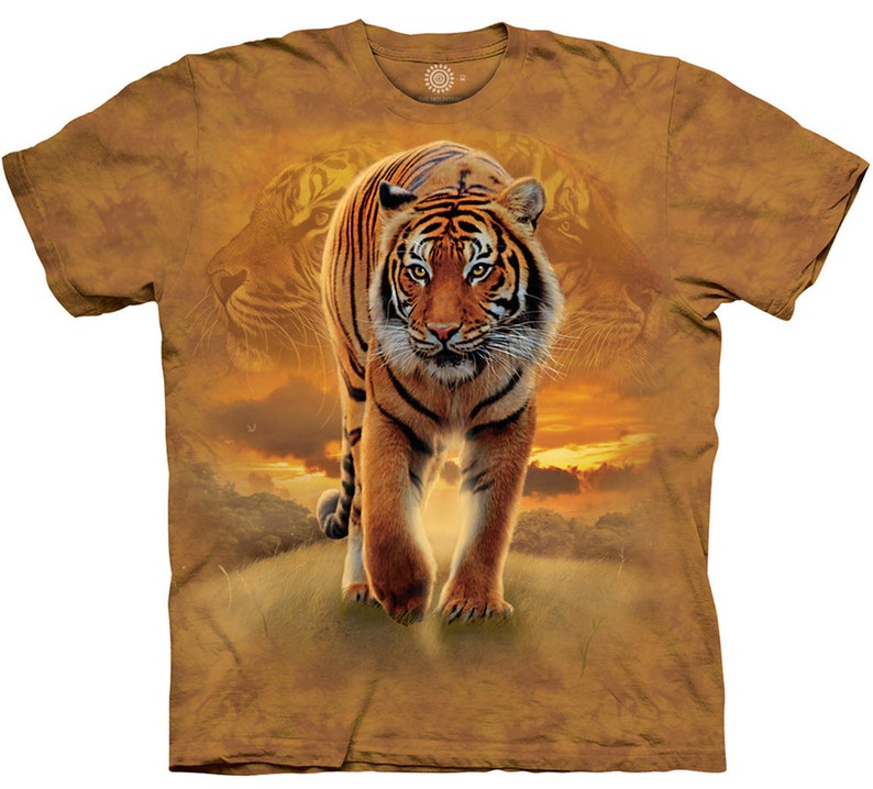 May include: A brown t-shirt with a tie-dye pattern featuring a tiger walking towards the viewer. The background is a sunset with clouds and a silhouette of trees.
