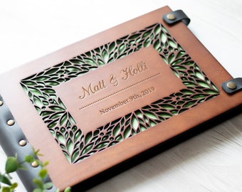 May include: Brown leather photo album with a cut-out design of green leaves and the text "Matt & Holli" and "November 9th, 2019".