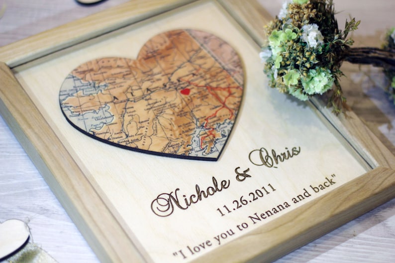 Close-up of custom map art on wood. Features a detailed map of Alaska with a personalized heart marker. Texture of the natural wood is visible, highlighting the rustic style perfect for a 5th anniversary wood gift.