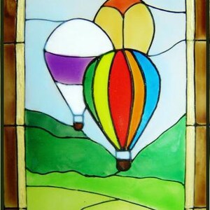May include: A stained glass window design featuring three hot air balloons in flight. The balloons are colorful, with one purple and white, one yellow and orange, and one red, yellow, blue, and green. The balloons are flying over a green landscape.