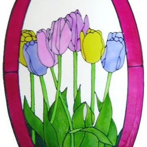 Puede incluir: Vidriera ovalada con tulipanes coloridos. Las flores son de color púrpura, amarillo y azul, con tallos y hojas verdes. El marco es de color rosa intenso. El texto "ALI'S CRAFT STUDIO : STUDIOCRAFTS.NET" está en la parte inferior.