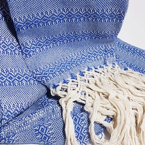 Peut inclure: Un ch&acirc;le tiss&eacute; bleu et blanc avec une frange. Le ch&acirc;le a un motif g&eacute;om&eacute;trique.