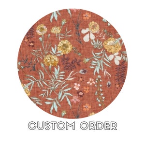 Puede incluir: Una tela redonda de color rojo con un patrón floral. La tela presenta una variedad de flores en tonos de amarillo, naranja y rosa, así como hojas verdes. La tela tiene una superficie texturizada y un aspecto rústico. "CUSTOM ORDER" está impreso en texto negro en la parte inferior de la imagen.