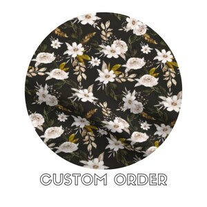 Puede incluir: Tela negra con un patrón floral blanco. Las flores son estilizadas y tienen un aspecto vintage. El fondo es negro oscuro.