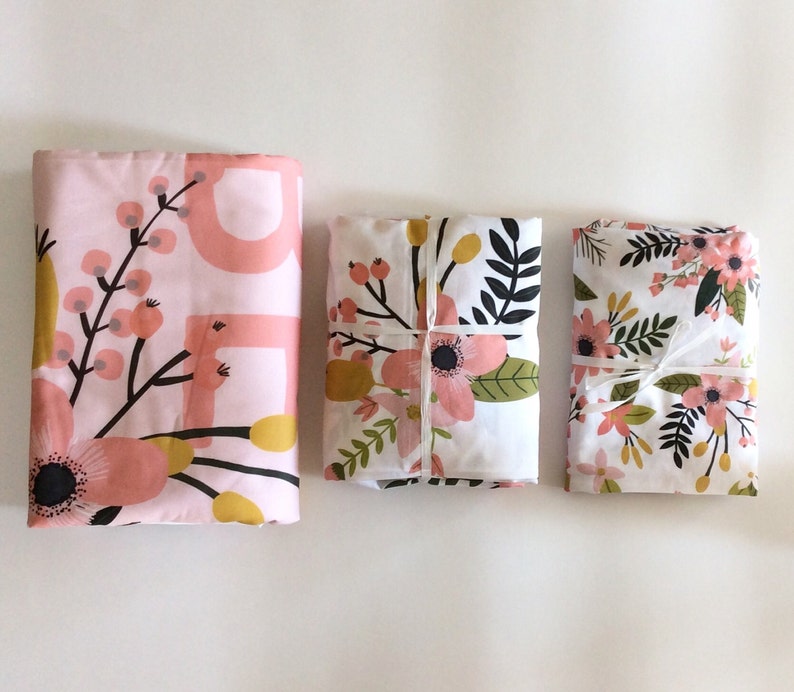 May include: Three fabric squares with floral patterns. The top square is pink with a floral design and white accents. The middle square is white with a pink and green floral design. The bottom square is white with a pink and green floral design.
