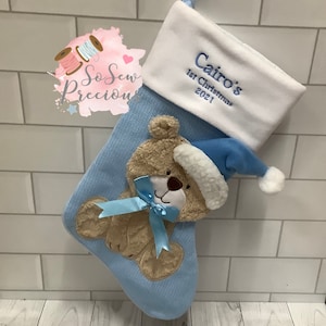 Può includere: Calza di Natale blu e bianca con un'applicazione a forma di orsacchiotto e il testo "Cairo's 1st Christmas 2021" ricamato sul polsino.