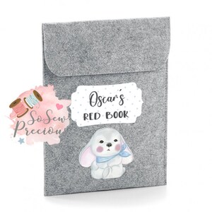 May include: Gray felt book sleeve with a white label that says "Oscar's Red Book" and a cartoon bunny with blue accents.