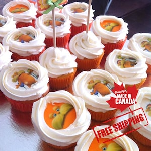 May include: A close-up of a dozen cupcakes decorated with white icing and edible images of a cartoon character. The cupcakes are arranged in a circle on a silver surface. The text "Proudly Made in Canada" and "Free Shipping" are visible in red.