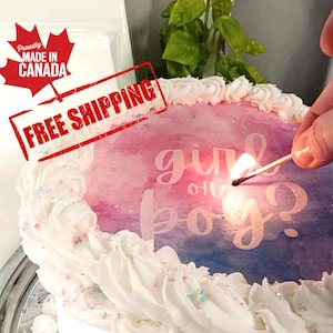 May include: A white cake with pink and blue frosting and sprinkles. The cake is decorated with a watercolour design and the words "girl or boy?" in white lettering. A lit match is being held over the cake.