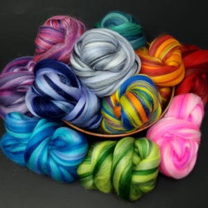 May include: A bowl filled with colourful rovings of wool fibre. The rovings are in shades of blue, green, pink, red, orange, yellow, and purple.