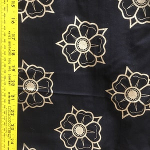 May include: Black fabric with a repeating pattern of gold stylized flowers. The flowers have a central circle with a smaller circle inside.