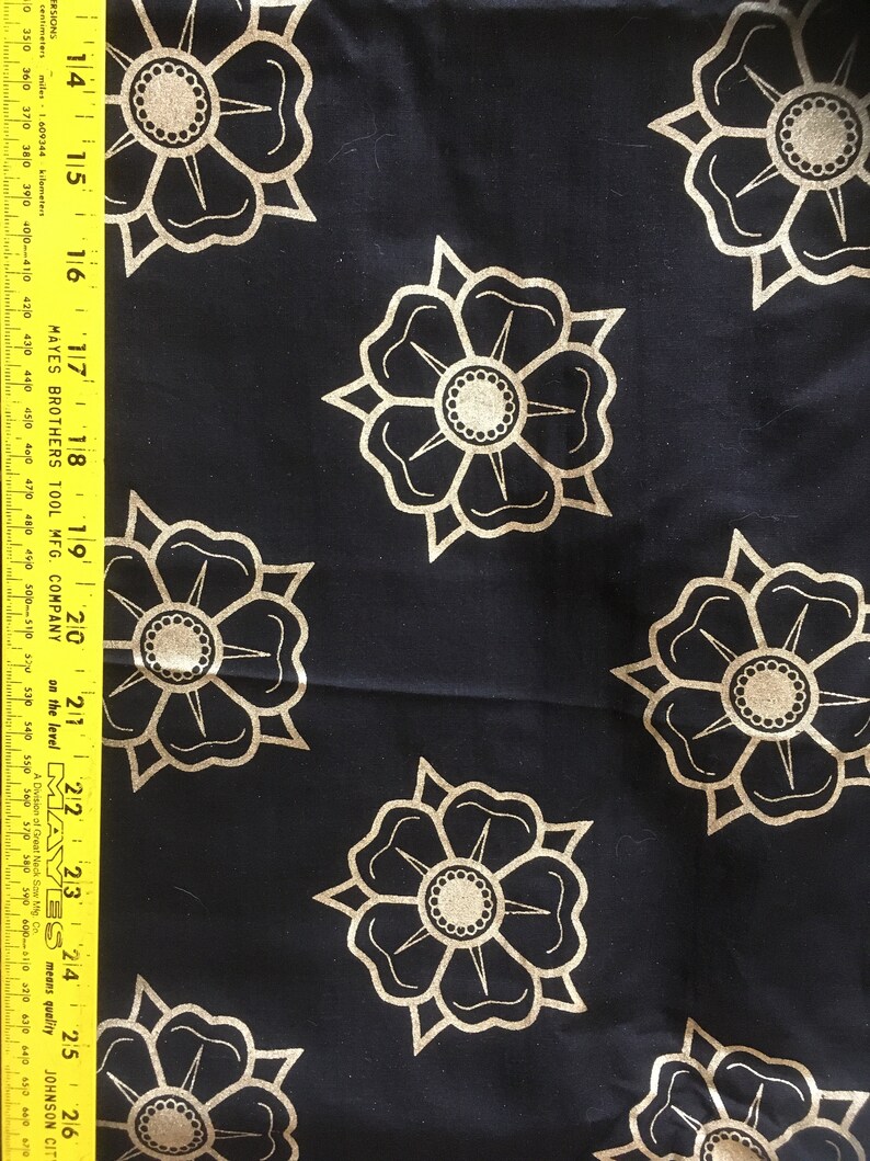May include: Black fabric with a repeating pattern of gold stylized flowers. The flowers have a central circle with a smaller circle inside.