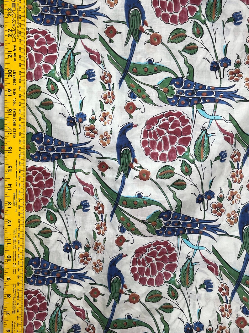 May include: White fabric with a repeating pattern of blue and green stylized birds, red and white flowers, and green leaves.