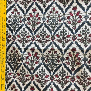 Puede incluir: Tela blanca con un patrón repetitivo de diseños florales estilizados en tonos rojos, azules y verdes. El patrón recuerda a los textiles tradicionales turcos u otomanos.