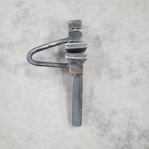 May include: A metal tool with a handle and a square head. The tool is made of a single piece of metal and has a unique shape.