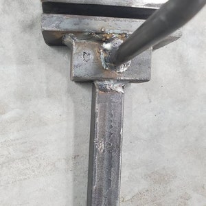 May include: Close-up of a metal tool with a heart-shaped mark. The tool is made of steel and has a rectangular shape. It appears to be a blacksmithing tool.