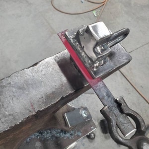 May include: A metal piece is being shaped on an anvil with a hammer. The metal is red hot and glowing. The anvil is made of iron and has a rough surface. The hammer is made of metal and has a wooden handle.