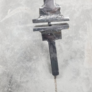 May include: A black metal blacksmithing tool with a long handle and a three-tiered top.