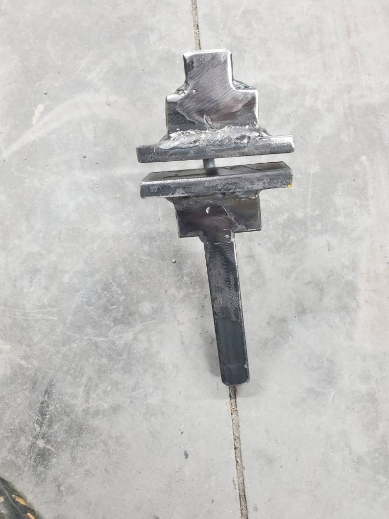 May include: A black metal blacksmithing tool with a long handle and a three-tiered top.