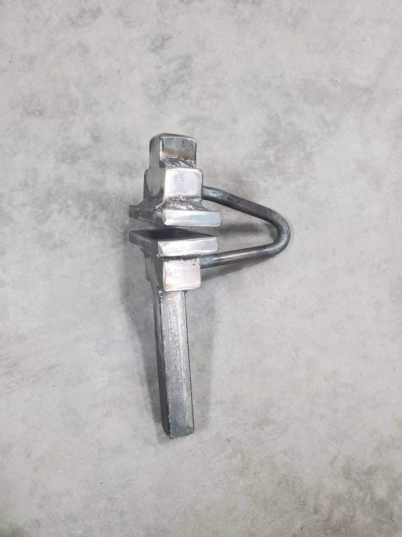 May include: A silver metal tool with a square head and a long handle. The tool has a loop on the side and is designed for tightening or loosening objects.