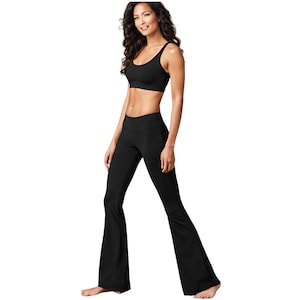 May include: A woman wearing a black sports bra and black flared yoga pants.